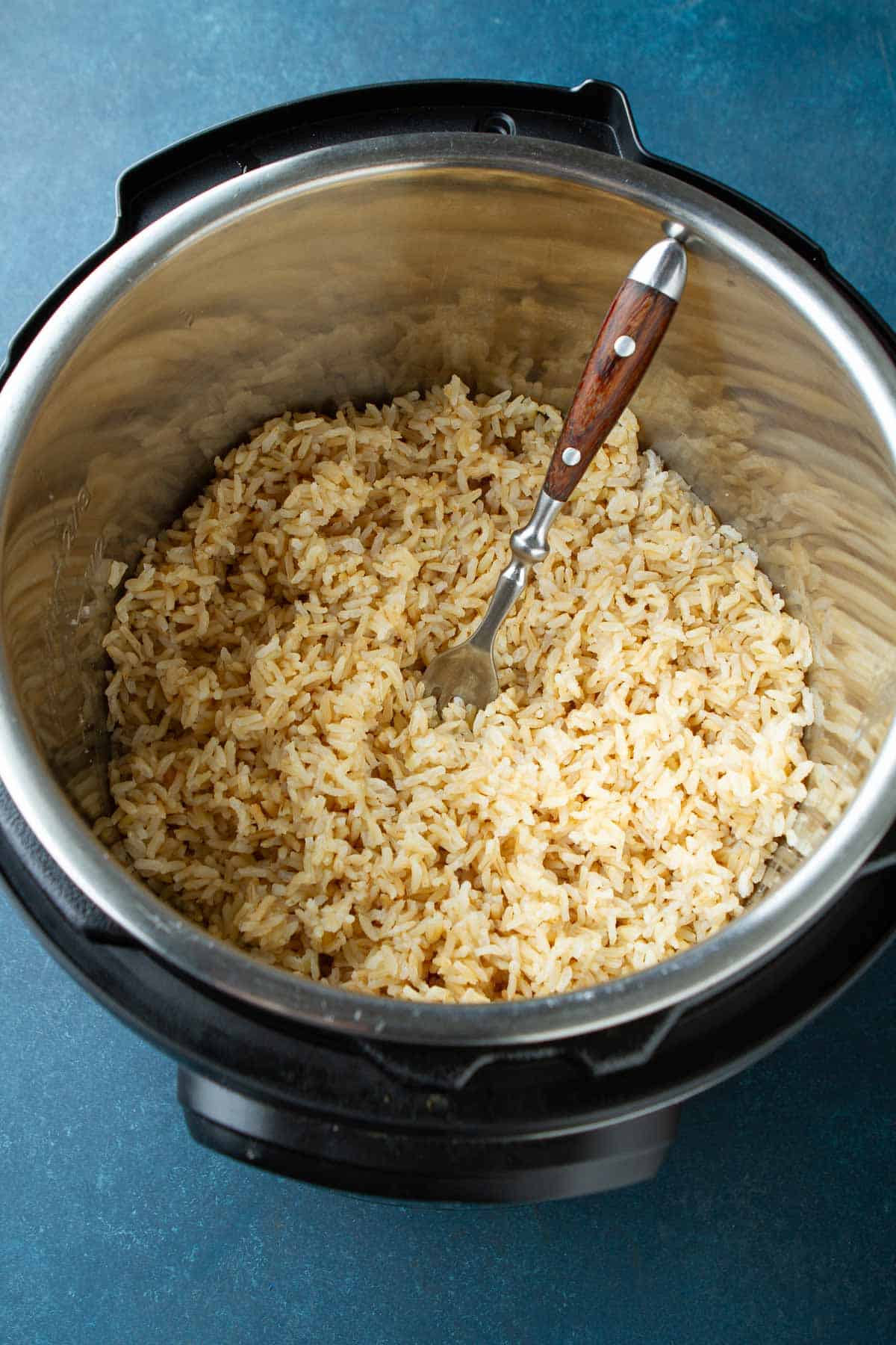 Cooked rice being fluffed with a fork in an Instant Pot.