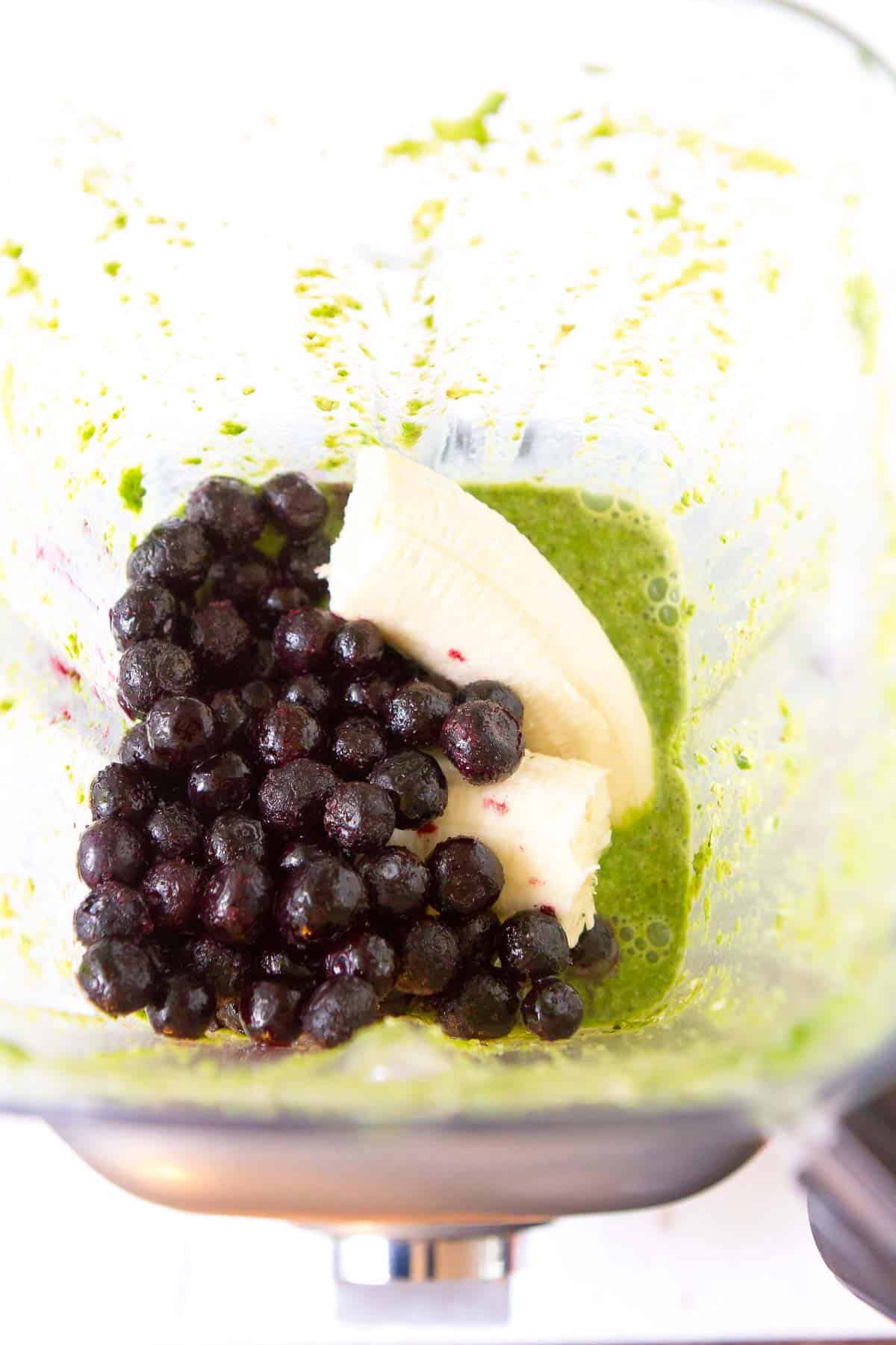 Frozen blueberries, banana and pureed spinach in a blender.