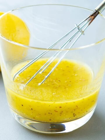 A whisk and lemon vinaigrette in a short glass.