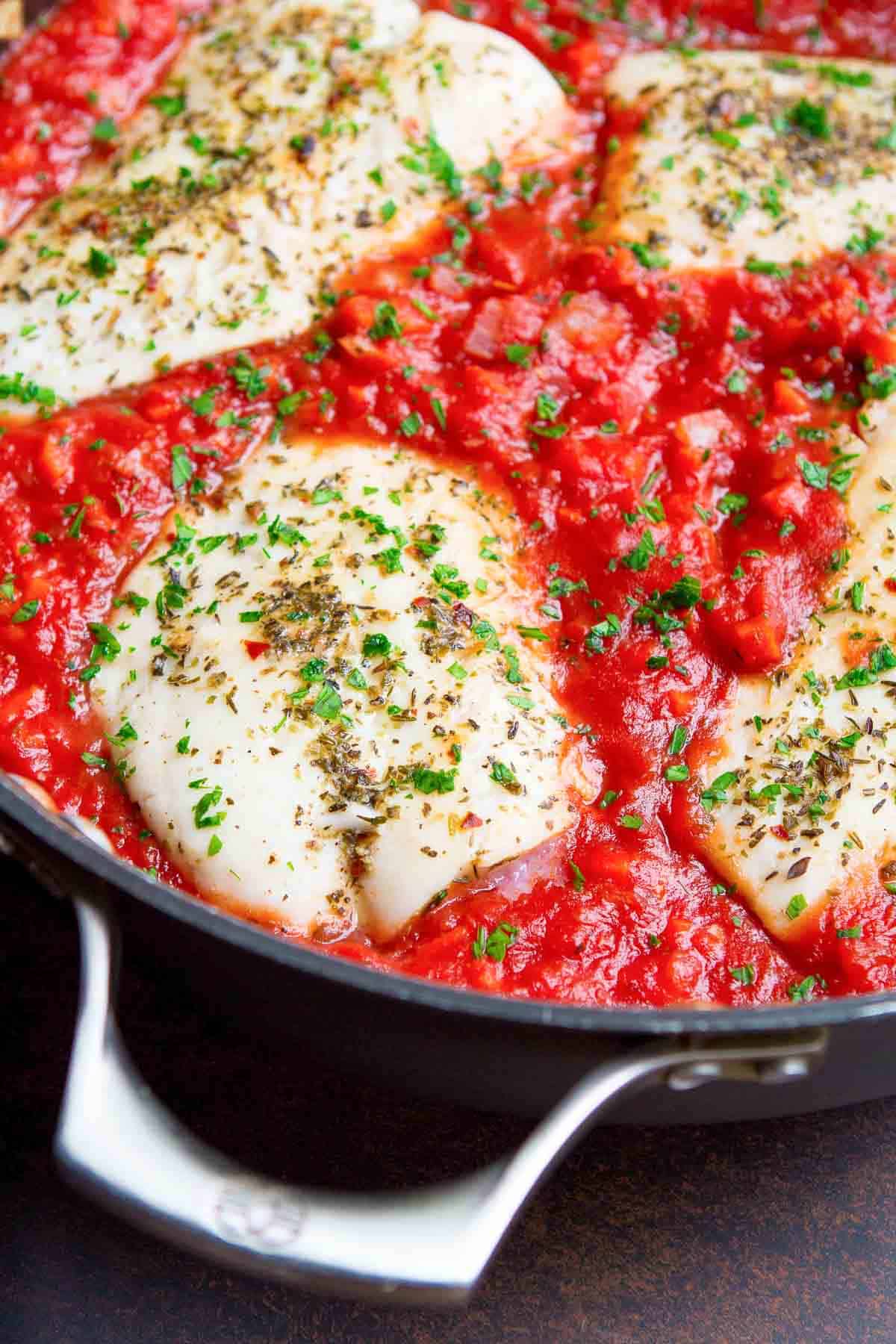 Cooked cod and tomato sauce in a large skillet.