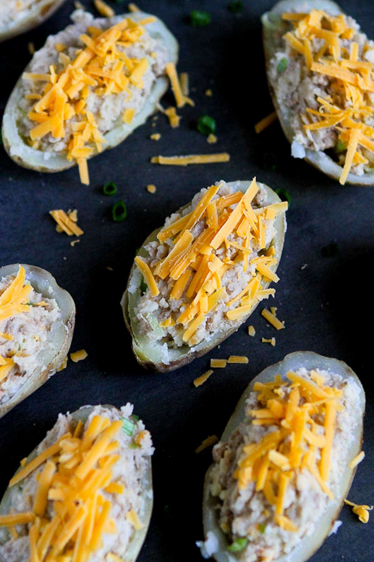 An overhead photo of multiple potato halves filled with a turkey mixture and topped with cheese.