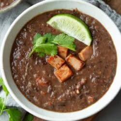 Black bean soup with hame and a lime wedge in a bowl.