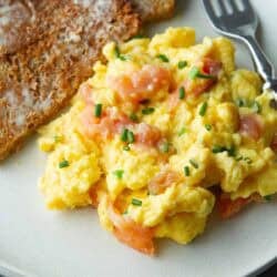Scrambled eggs with smoked salmon and toast on a plate.