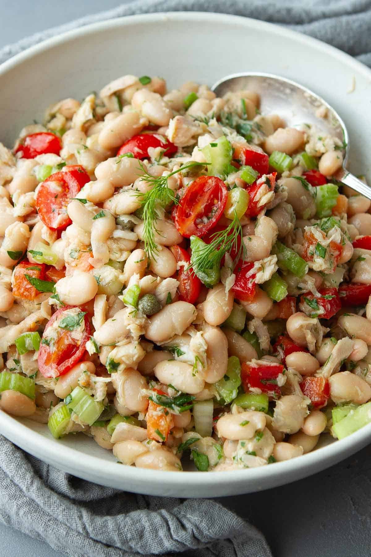 White bean salad with tuna and tomatoes in a white bowl.